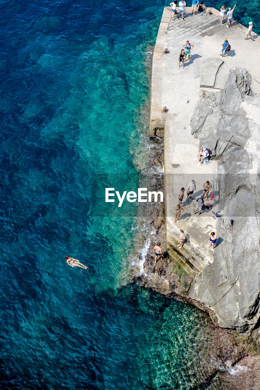 High angle view of people on rock by sea