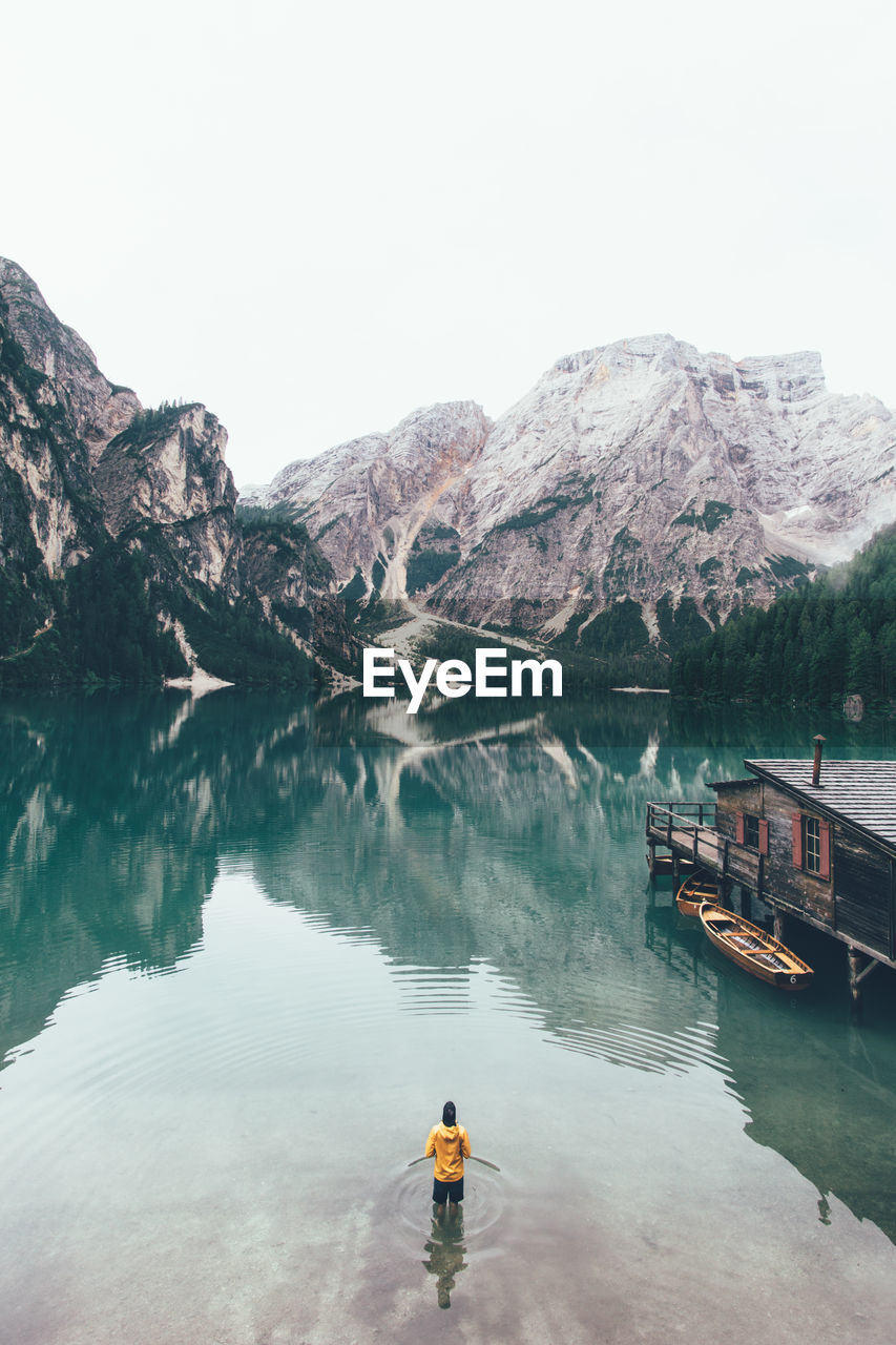 Rear view of man standing in pragser wildsee against dolomites