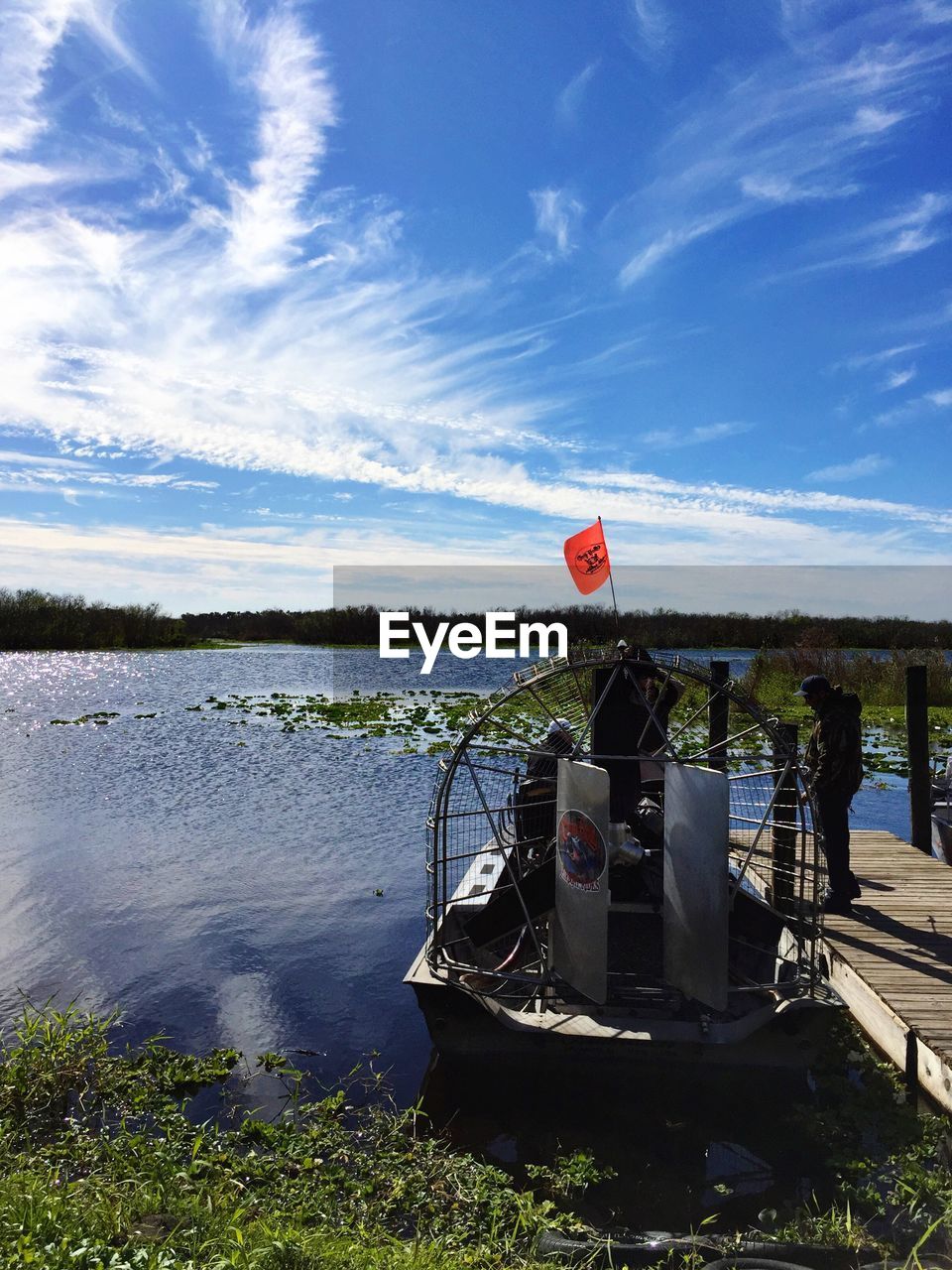 Boat moored by pier on lake against sky