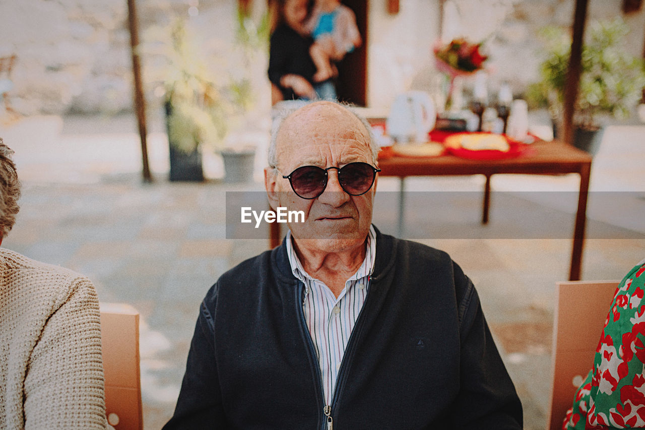 Portrait of young woman wearing sunglasses while standing in cafe