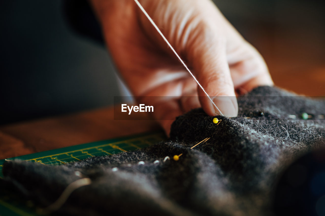 Close-up of cropped hand sewing textile in workshop