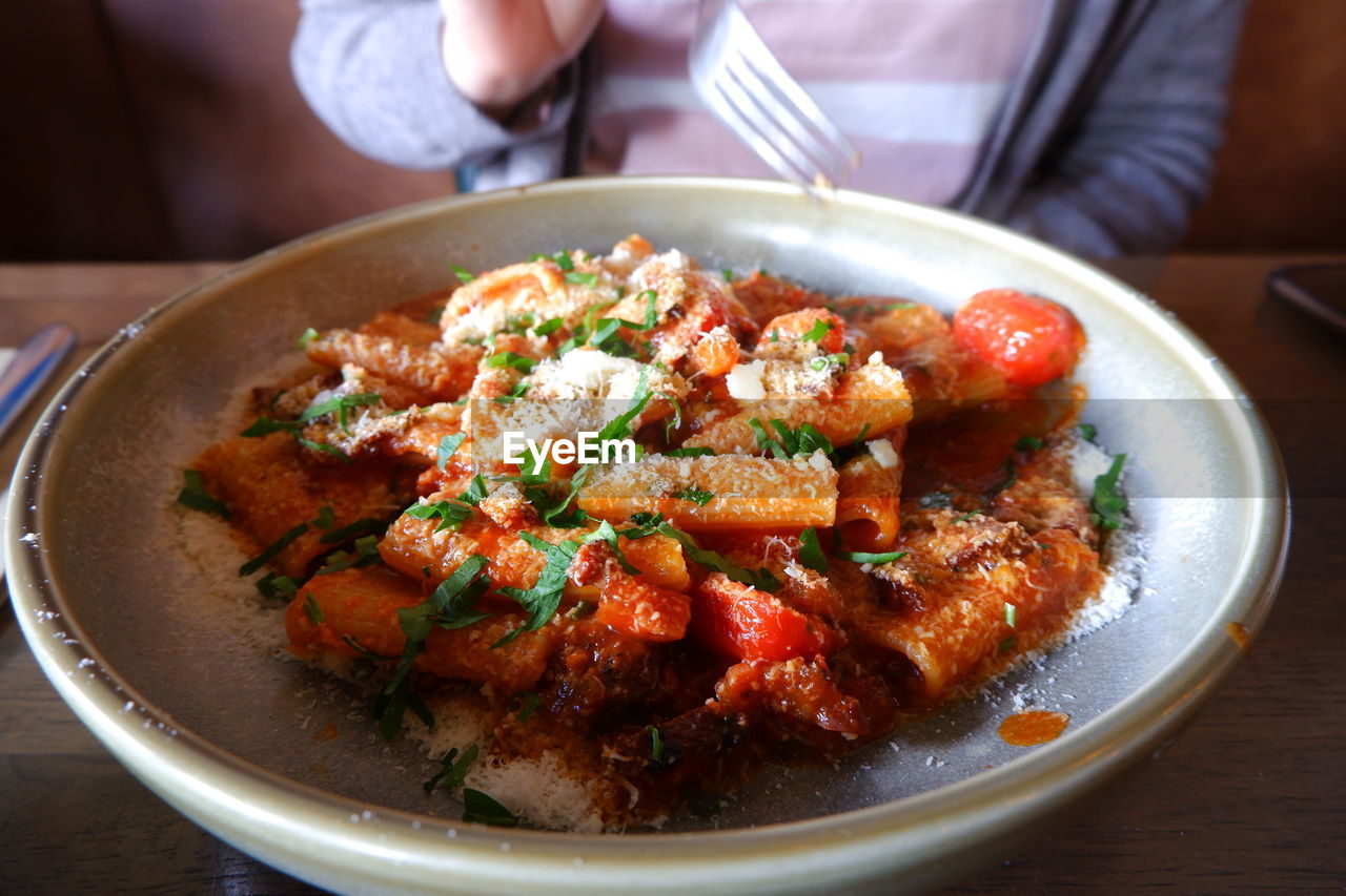 Midsection of woman sitting by food at restaurant