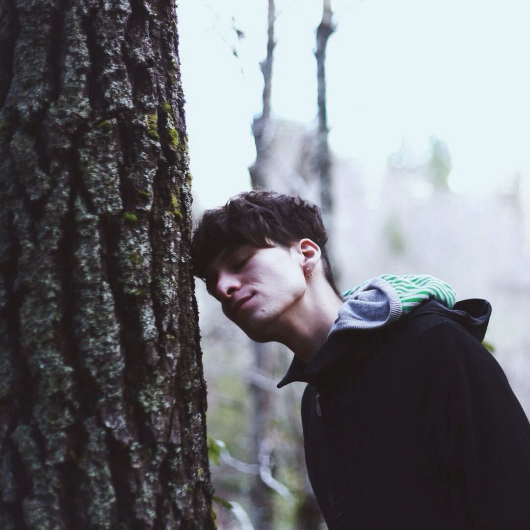 Man leaning against a tree trunk