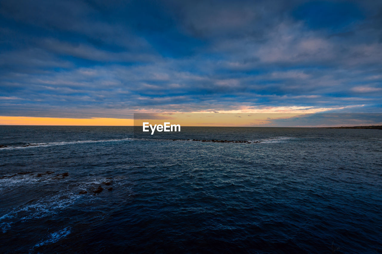 Sunset over the sea with cloudy sky and sun glow in the background