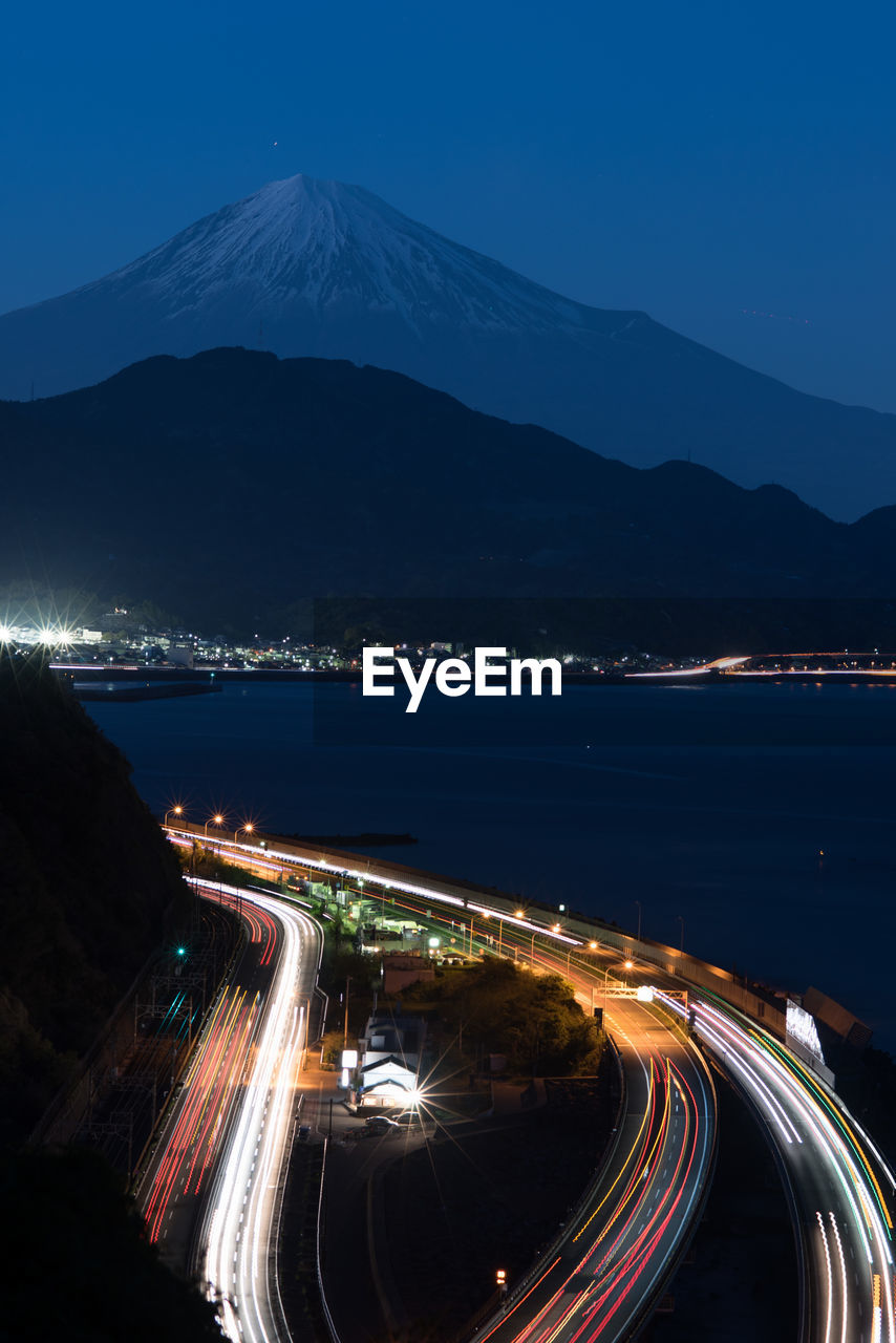 High angle view of light trails on road by mount fuji at night