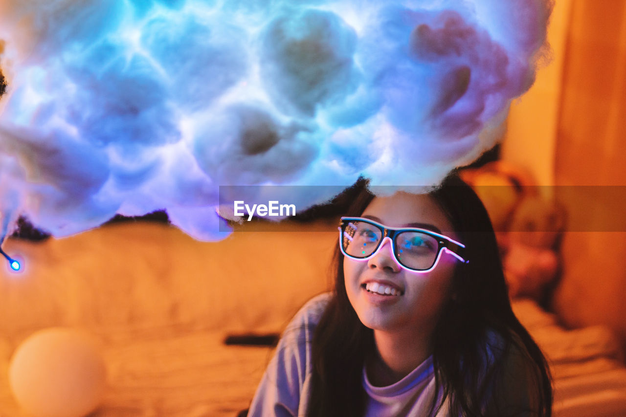 Smiling young woman looking at colorful cotton decoration in illuminated room