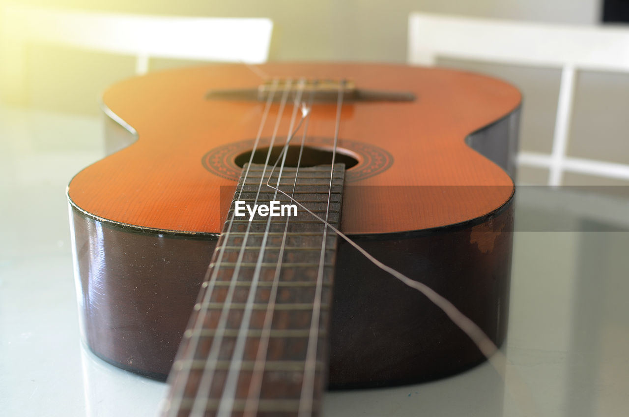 CLOSE-UP OF GUITAR ON TABLE AT HOME