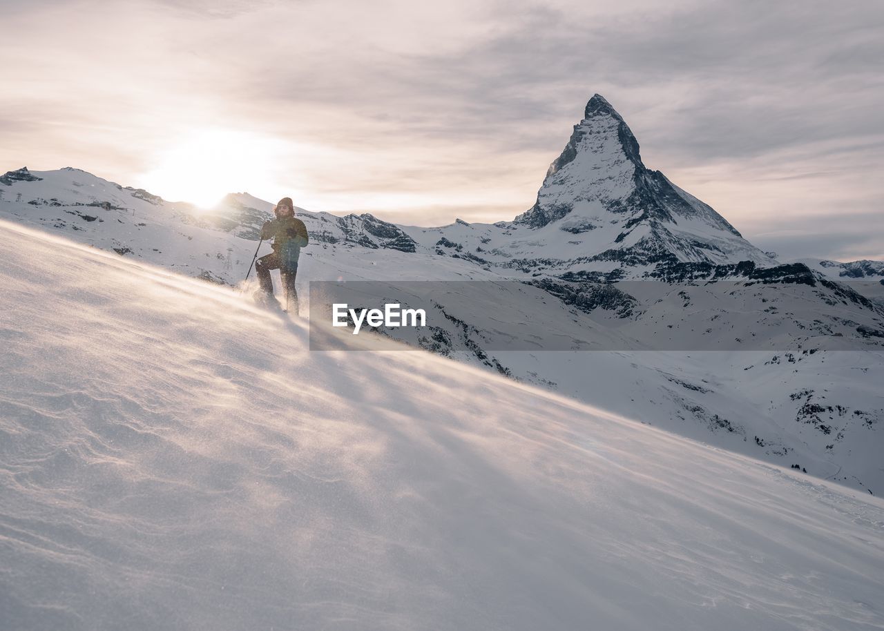 Man standing on snow covered mountain against sky