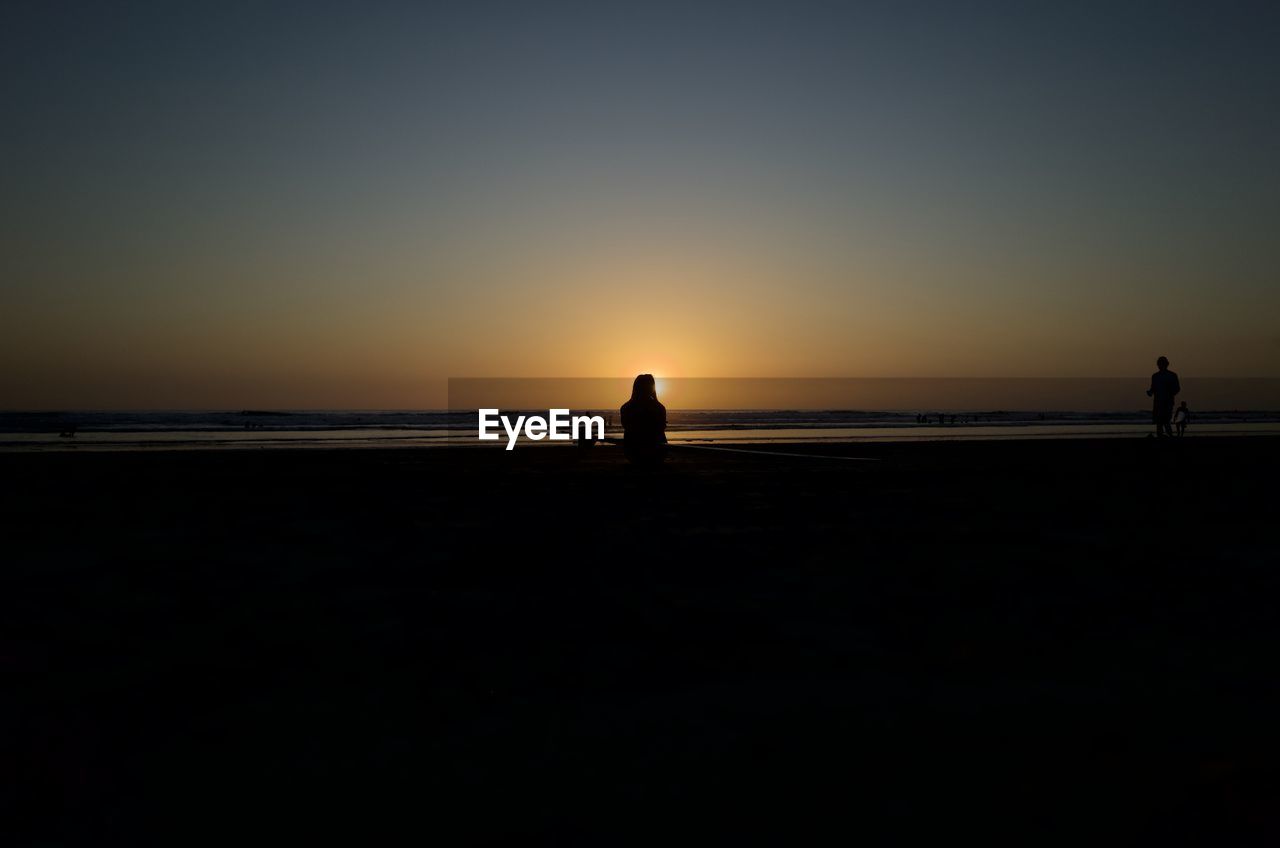 SILHOUETTE PEOPLE LOOKING AT SEA AGAINST CLEAR SKY