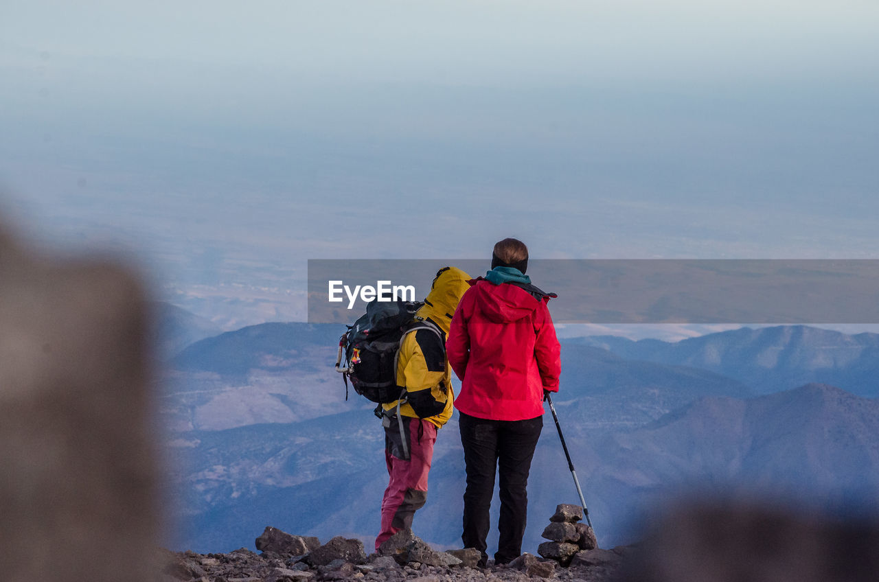 Hikers standing on mountain against sky