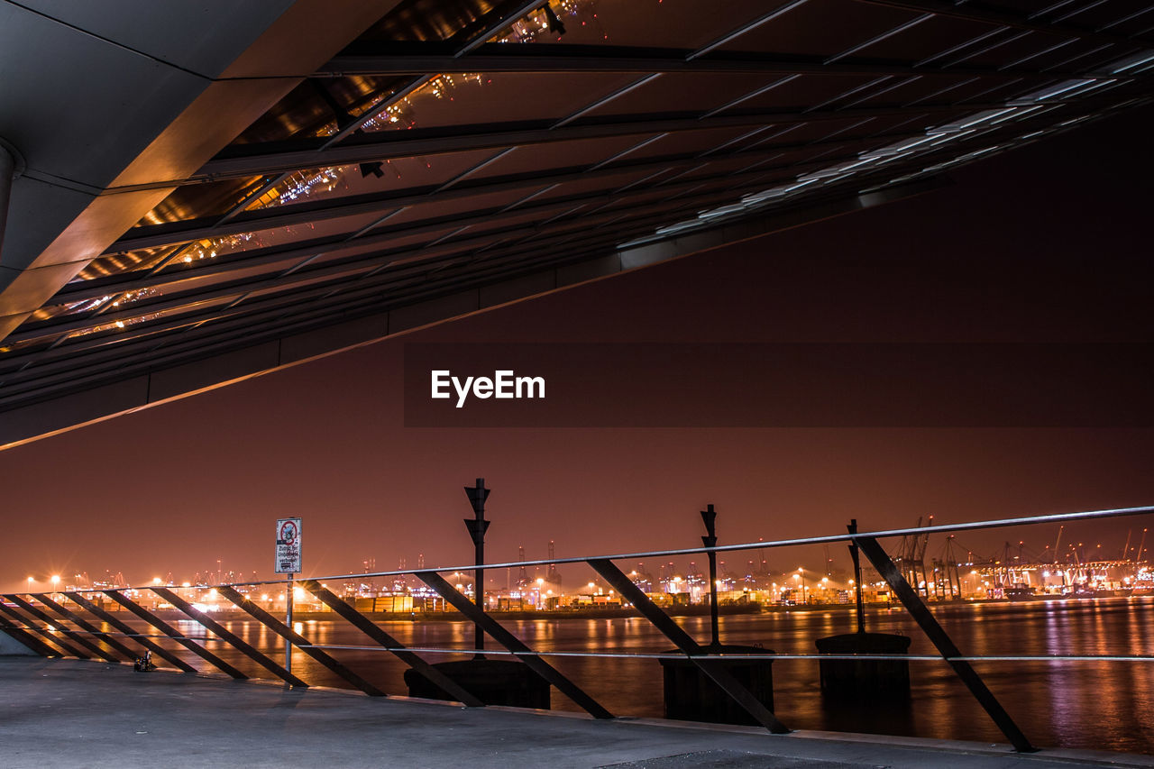 BRIDGE OVER RIVER AGAINST SKY AT NIGHT