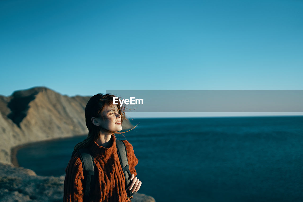 WOMAN LOOKING AT SEA AGAINST SKY