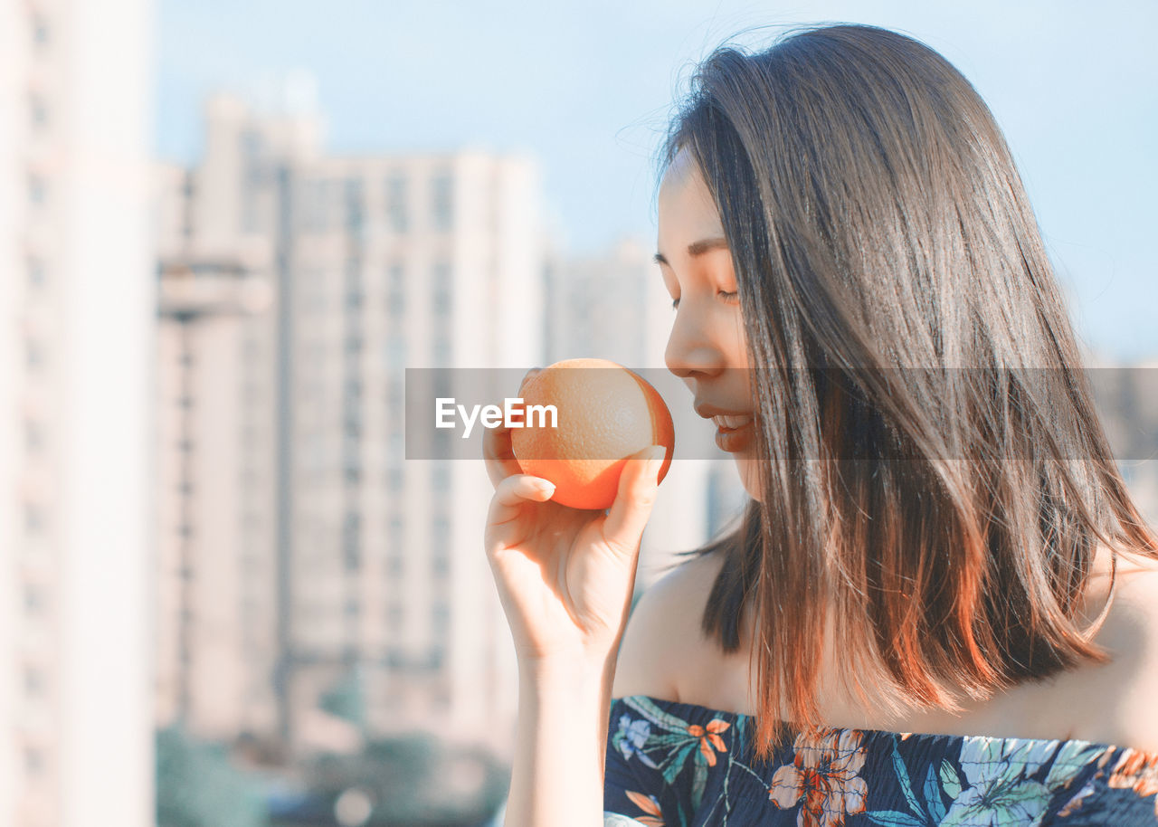 Woman holding orange in city