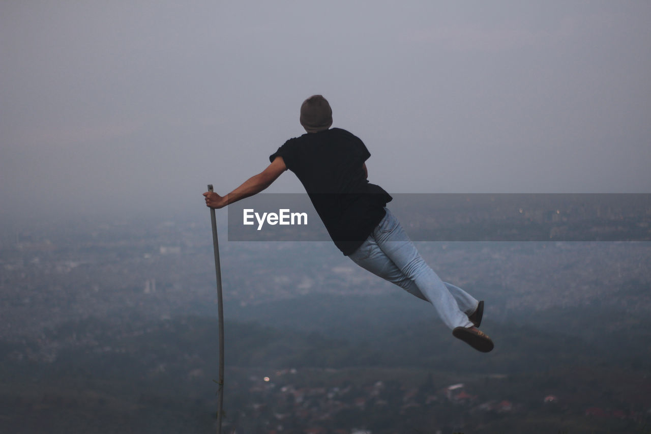 Rear view of man balancing on stick