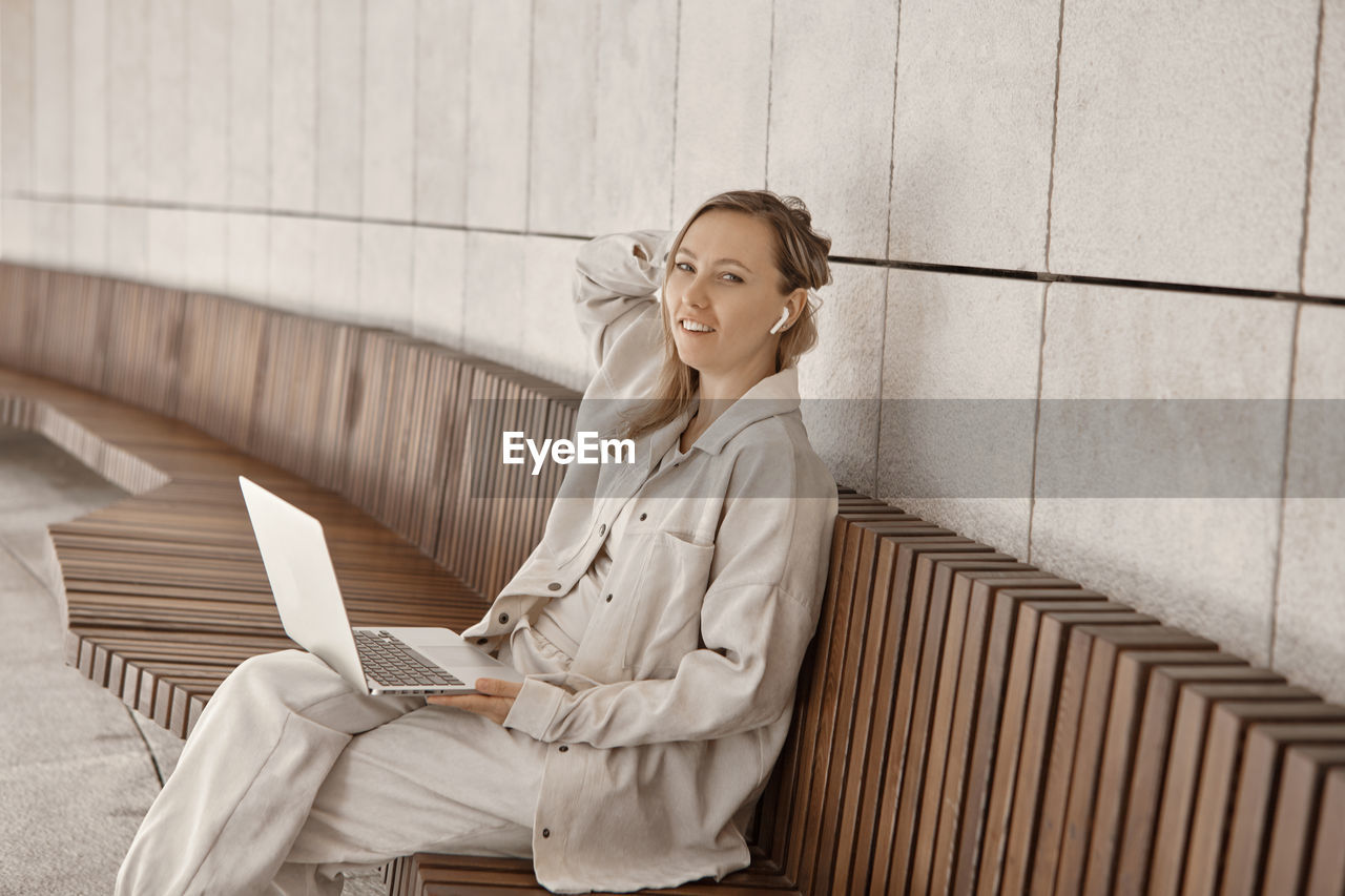 Portrait of woman using laptop while sitting on bench