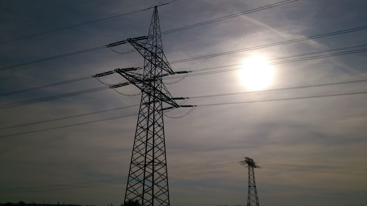 Low angle view of silhouette electricity pylon against sky