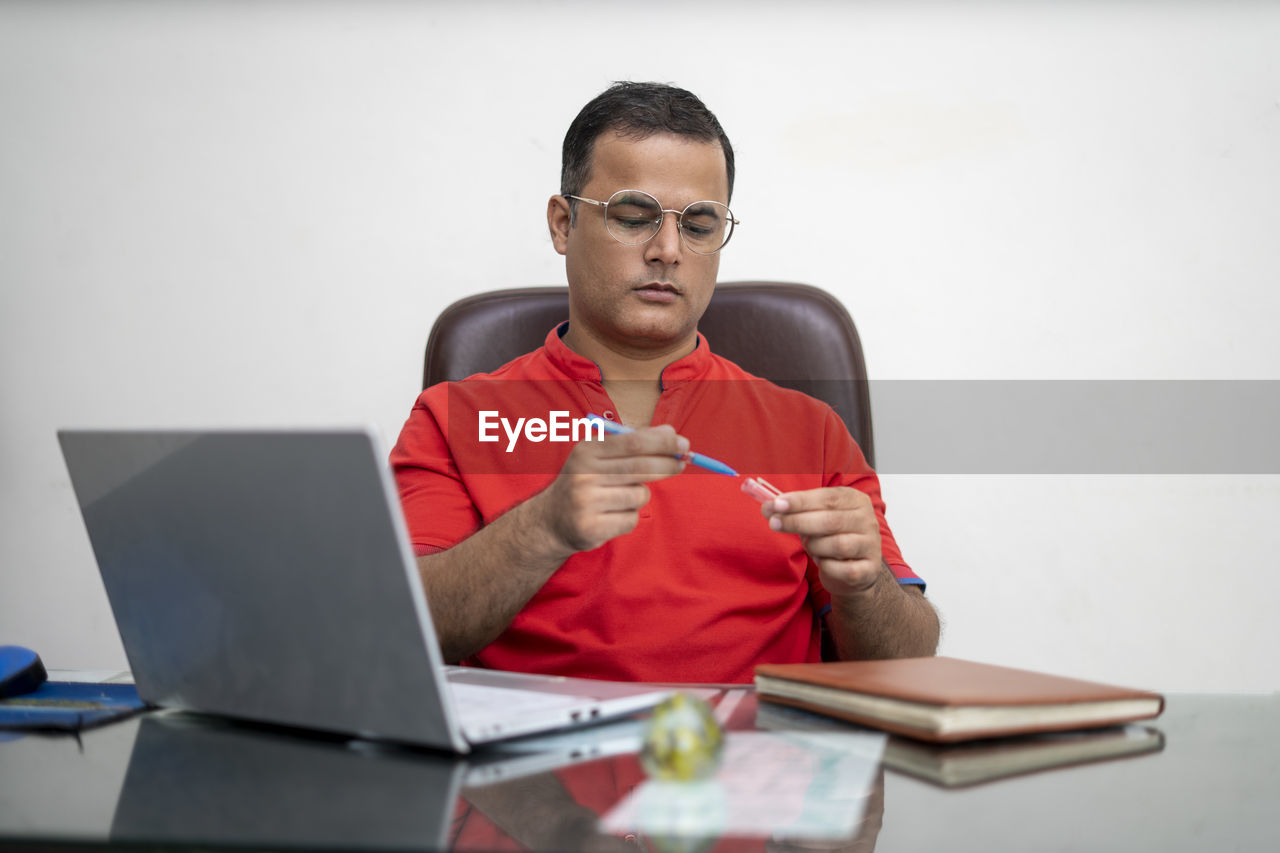 MID ADULT MAN USING LAPTOP IN MOBILE PHONE