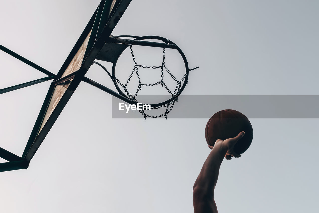 Silhouette of the hand of a basketball player throwing the ball into the ring.