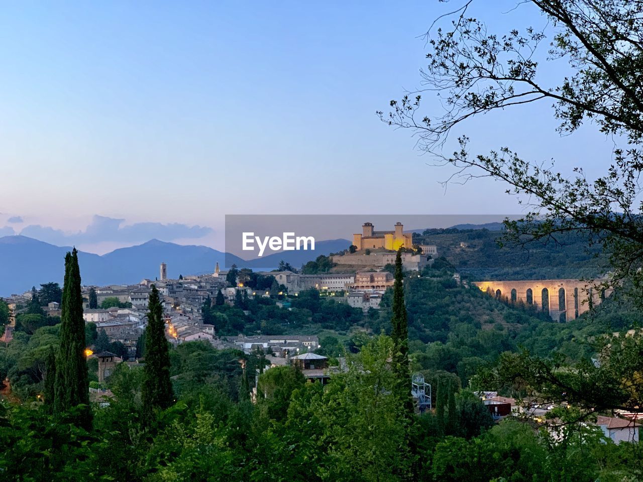 Trees, italian fort and aquaduct landscape shot of spoleto in umbria illuminated at dusk.