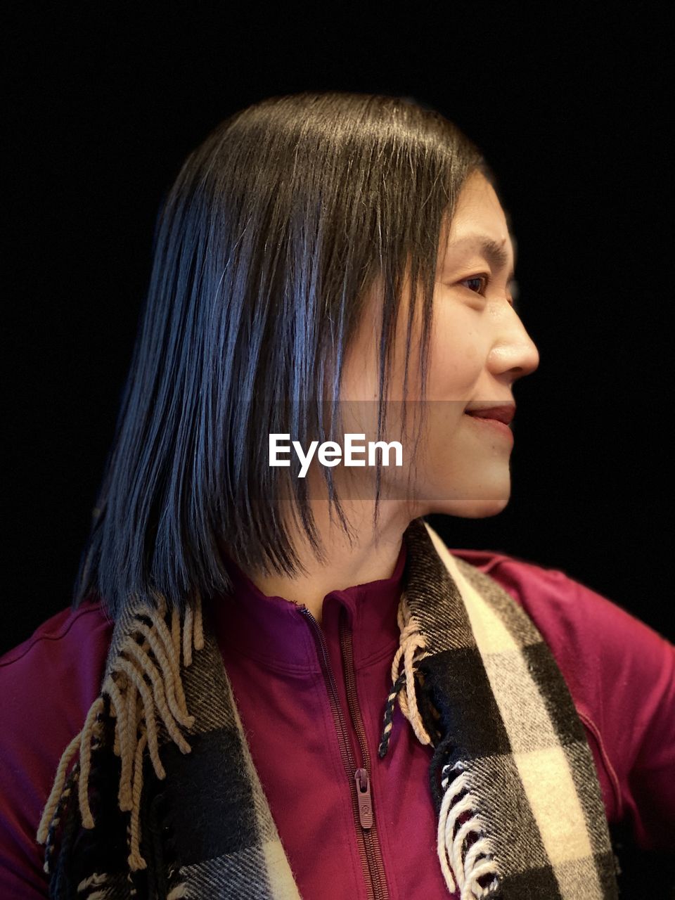 Smiling woman looking away against black background