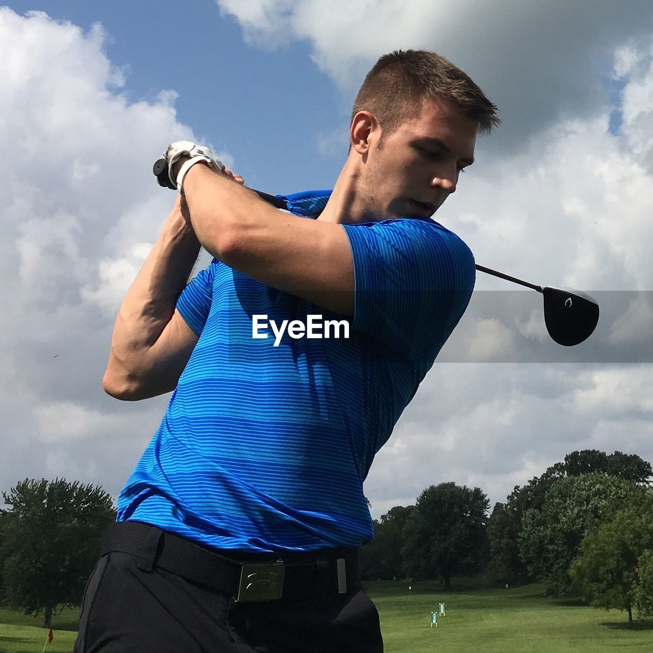 Young man playing golf against cloudy sky