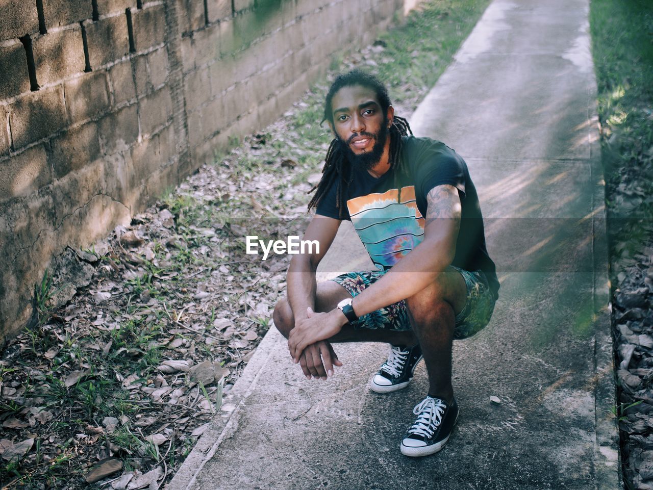 Portrait of man crouching on footpath