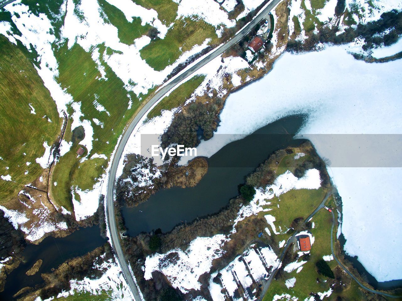 HIGH ANGLE VIEW OF FROZEN LAKE BY TREES