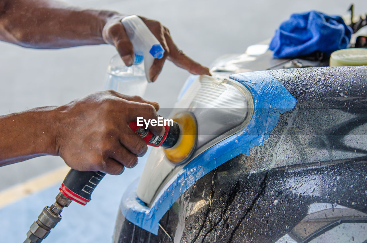 Cropped hand of man cleaning car with equipment