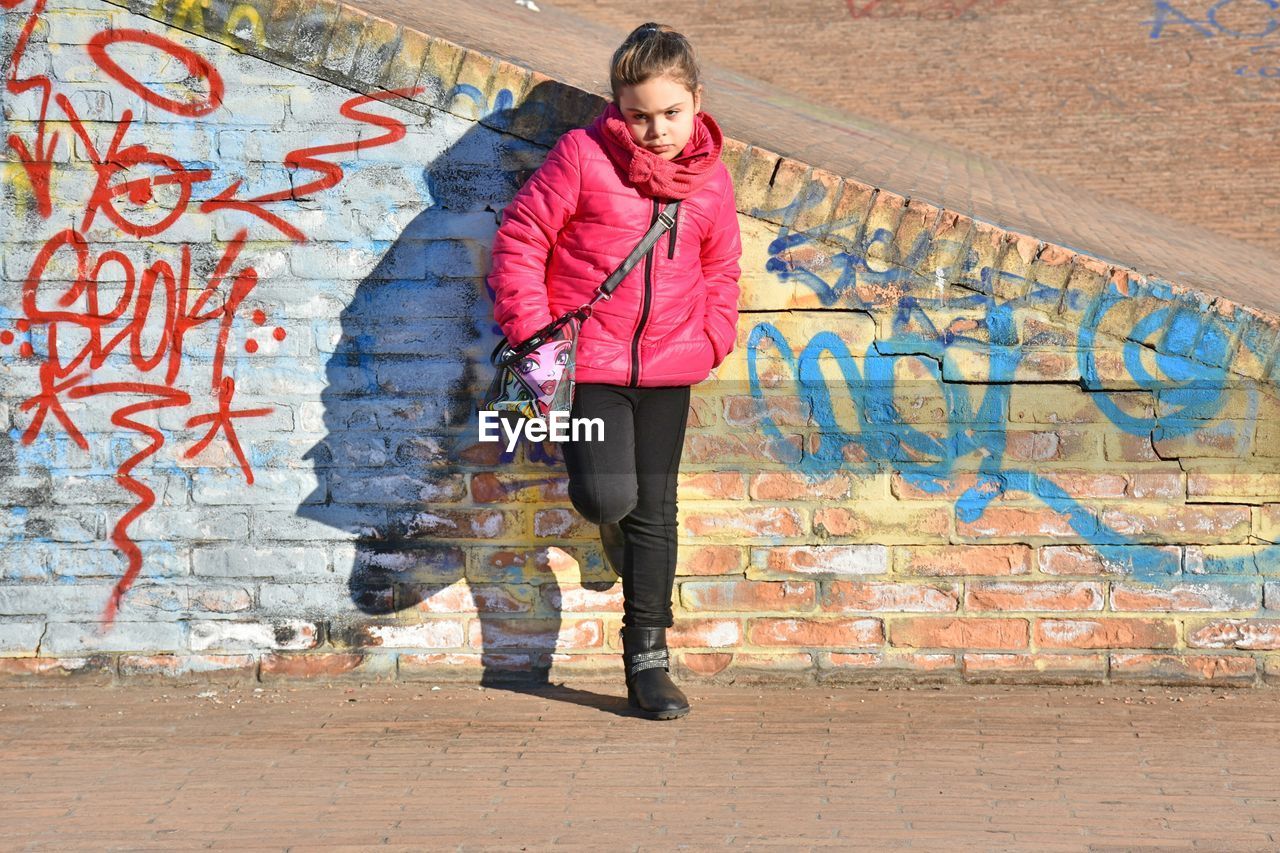 Full length of girl standing against graffiti in city