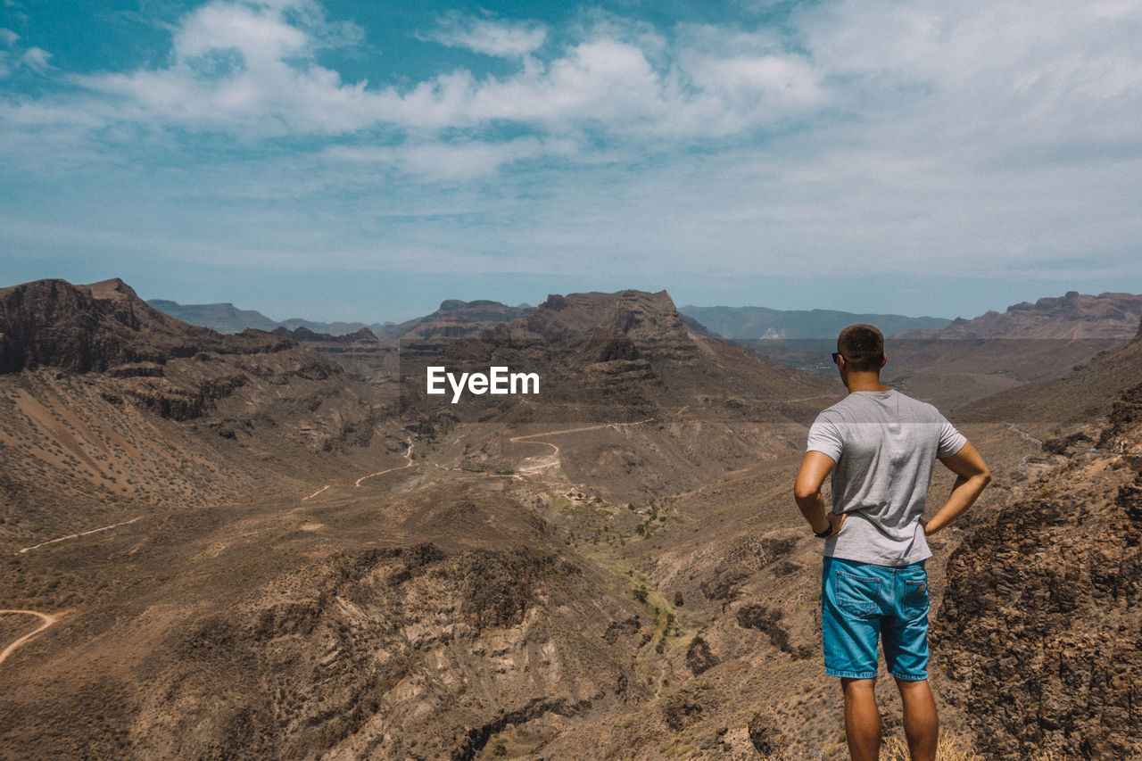 Rear view of man on mountain against sky