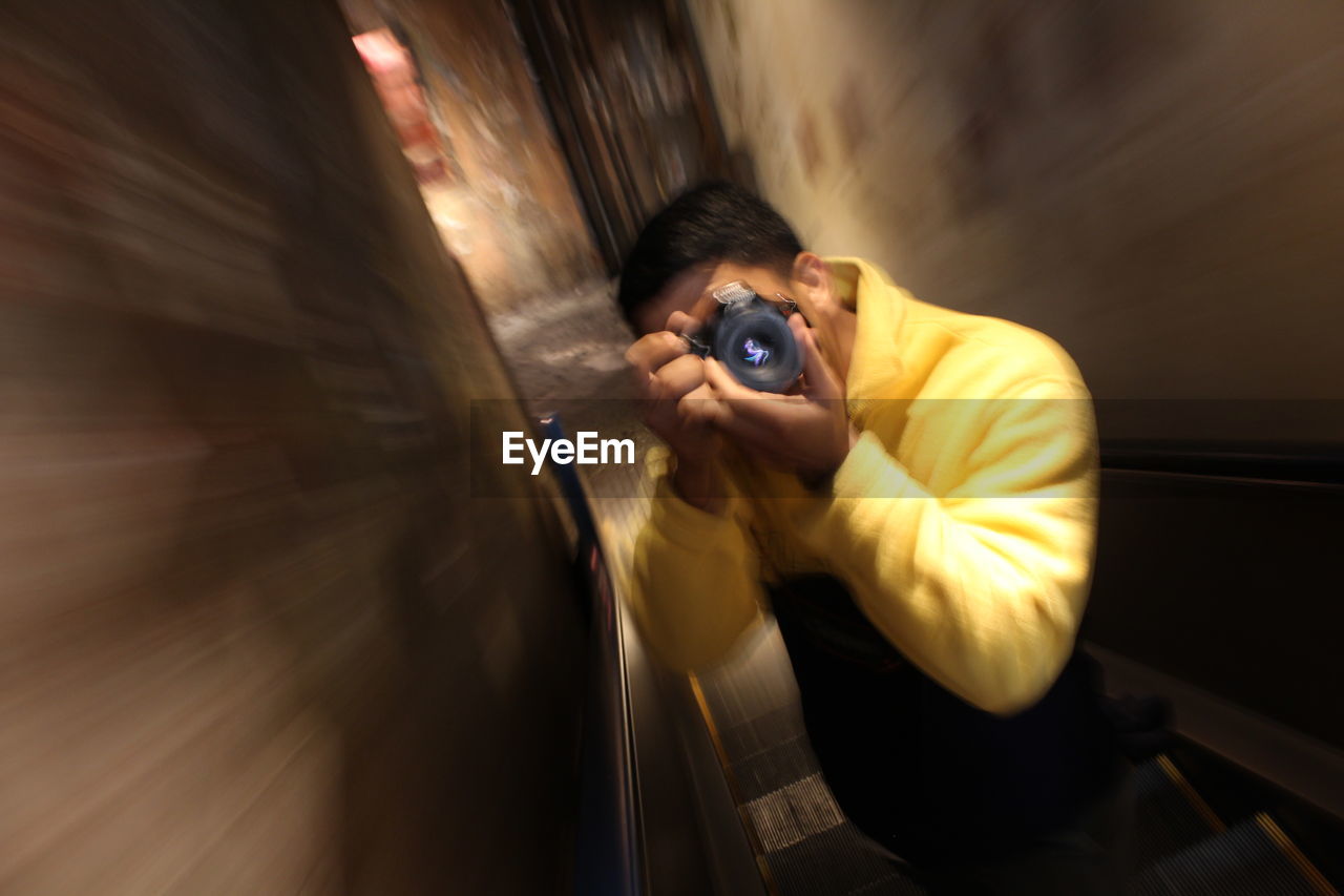 Blurred motion of man photographing through camera in darkroom