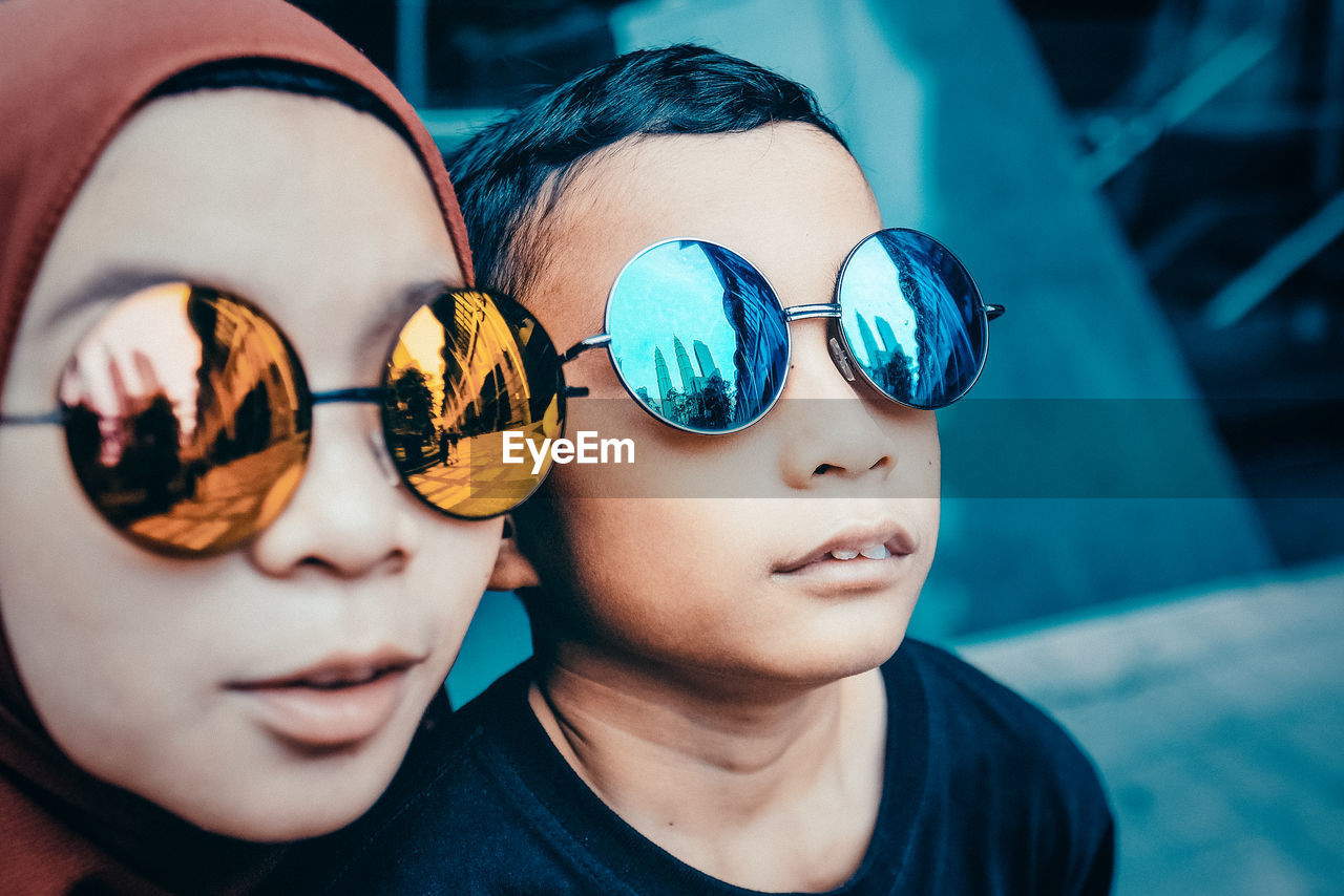 Close-up of siblings wearing sunglasses outdoors