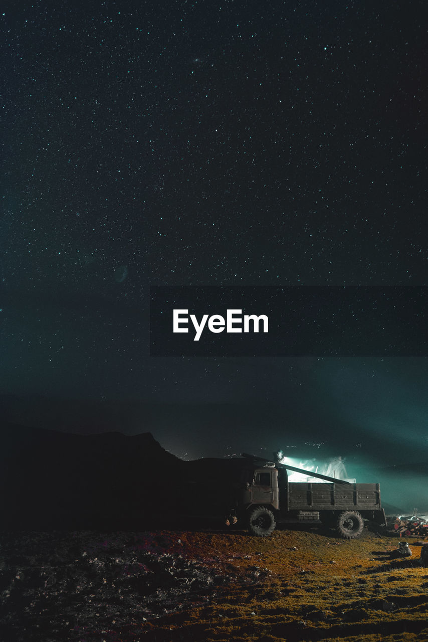 Illuminated car on field against sky at night