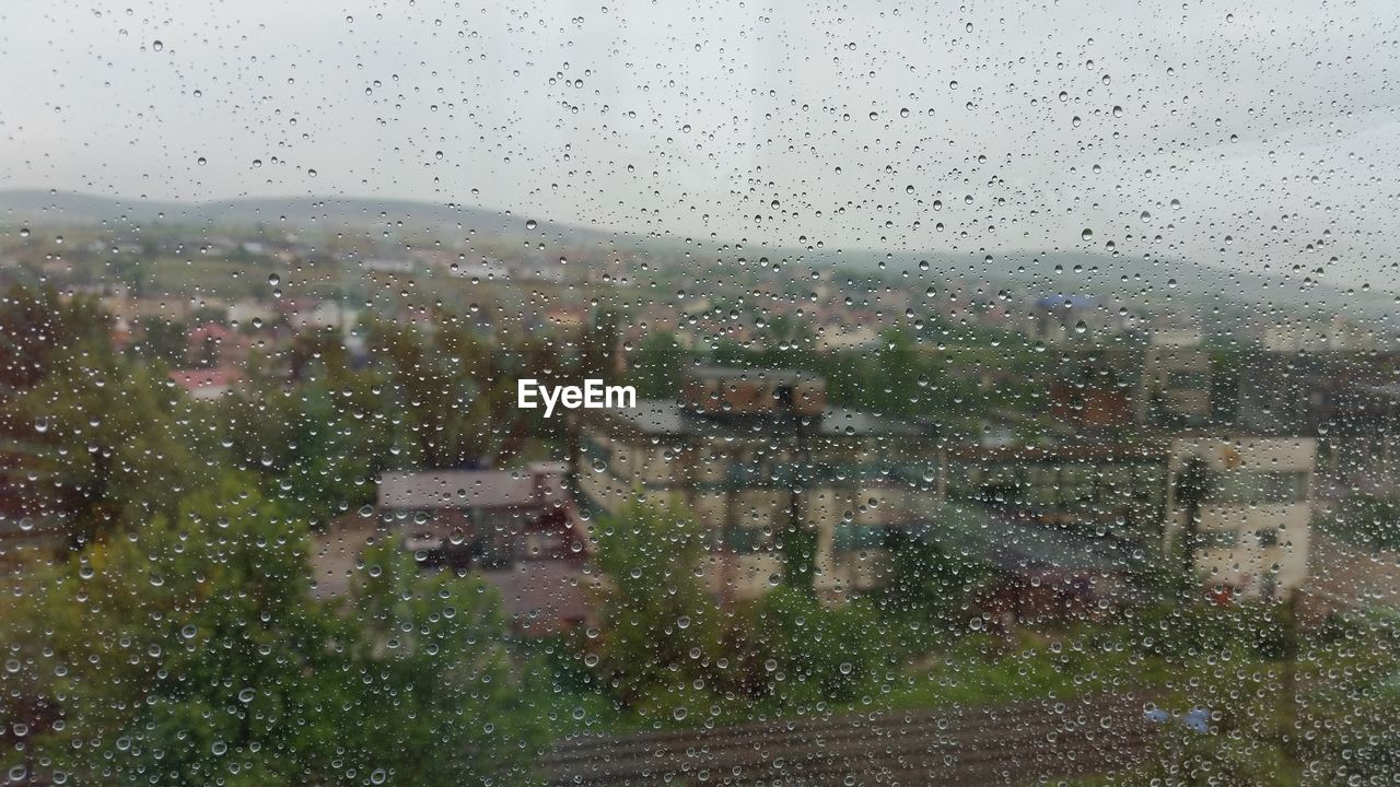 VIEW OF CITYSCAPE THROUGH WET WINDOW