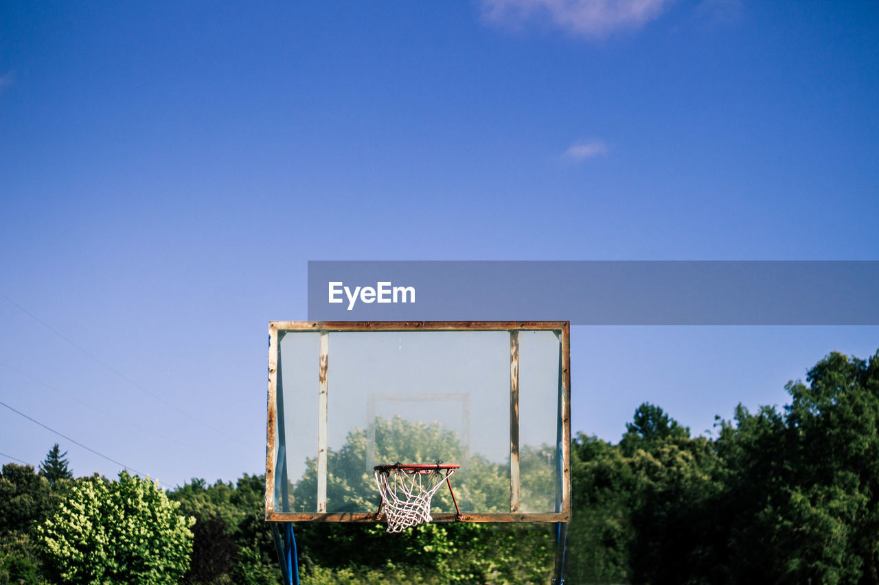 Basketball court against trees and blue sky