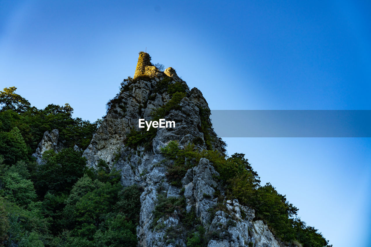 LOW ANGLE VIEW OF ROCK FORMATION AGAINST BLUE SKY