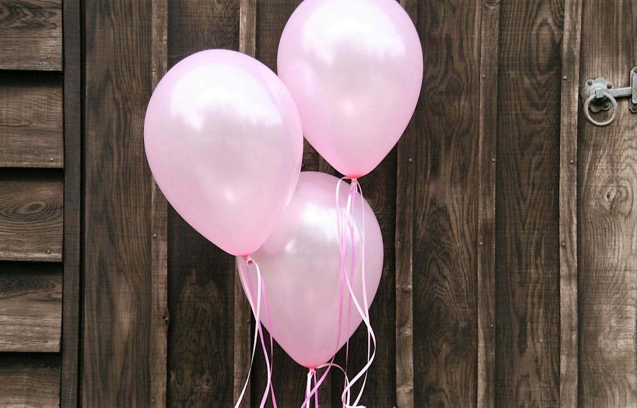 CLOSE-UP OF PINK BALLOONS AGAINST WALL