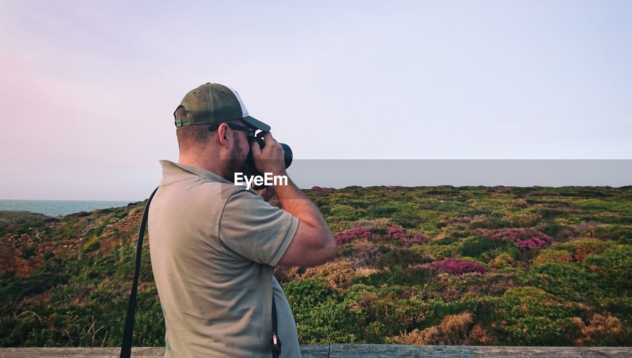 Man photographing on landscape against clear sky