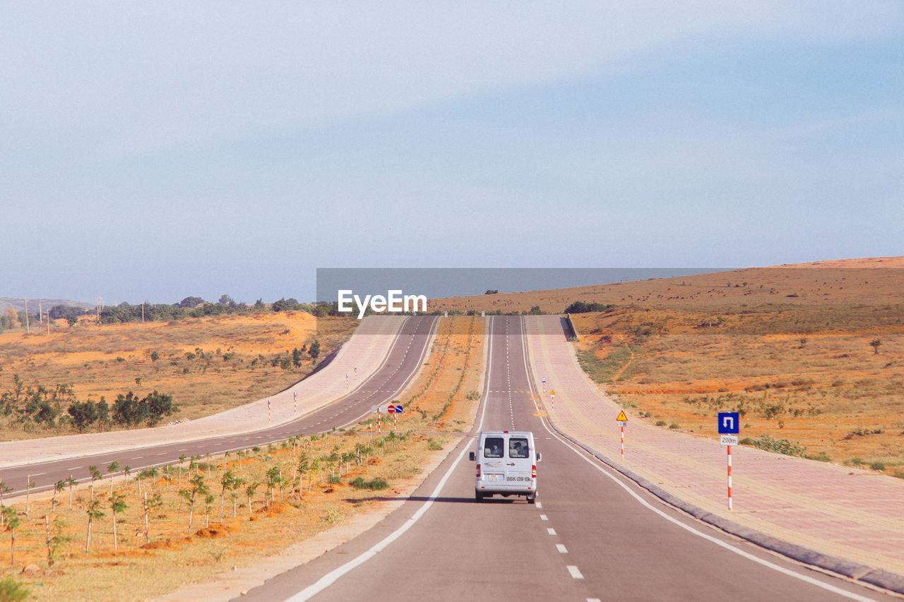 Car on road in desert against sky