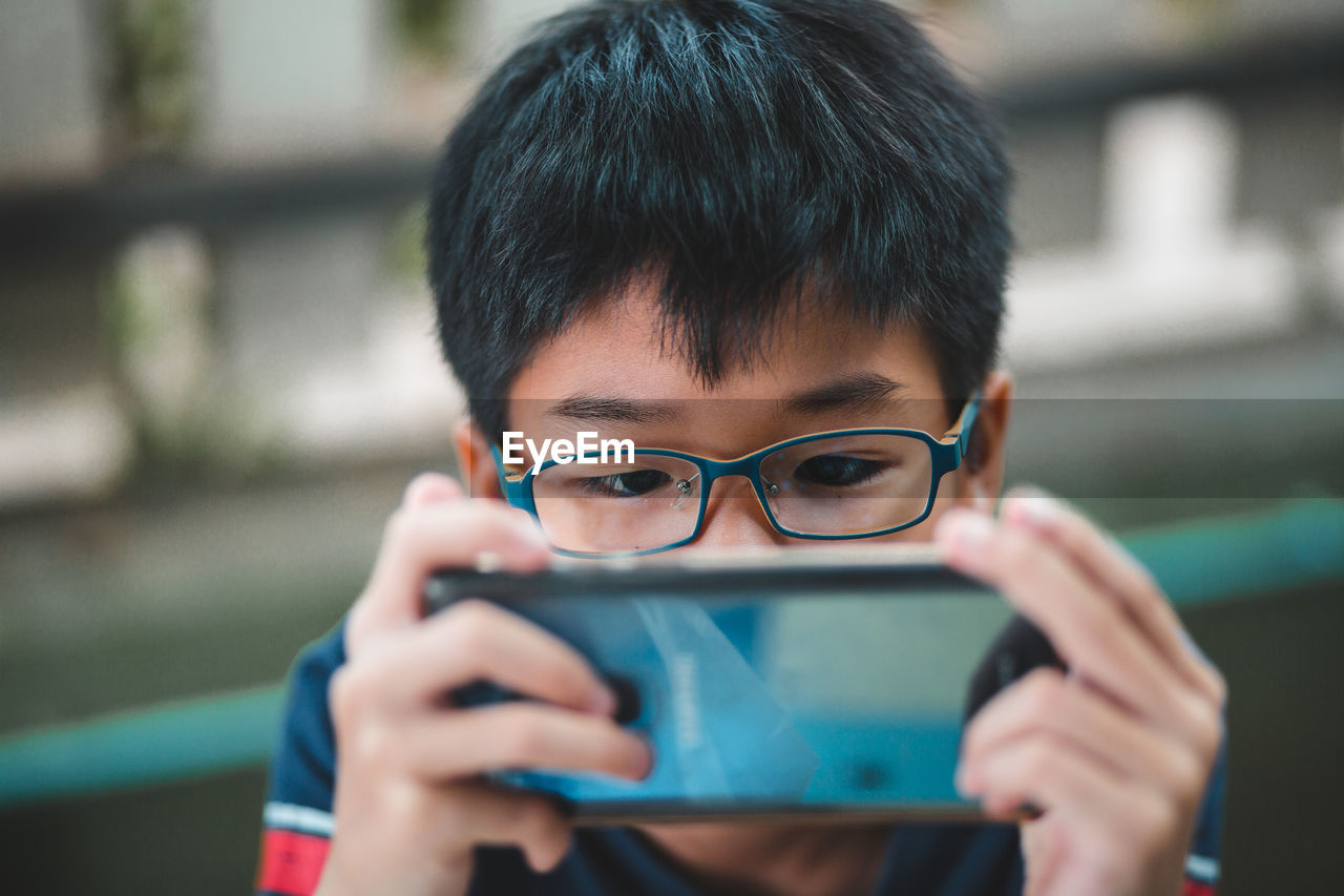 CLOSE-UP PORTRAIT OF BOY PHOTOGRAPHING THROUGH MOBILE PHONE