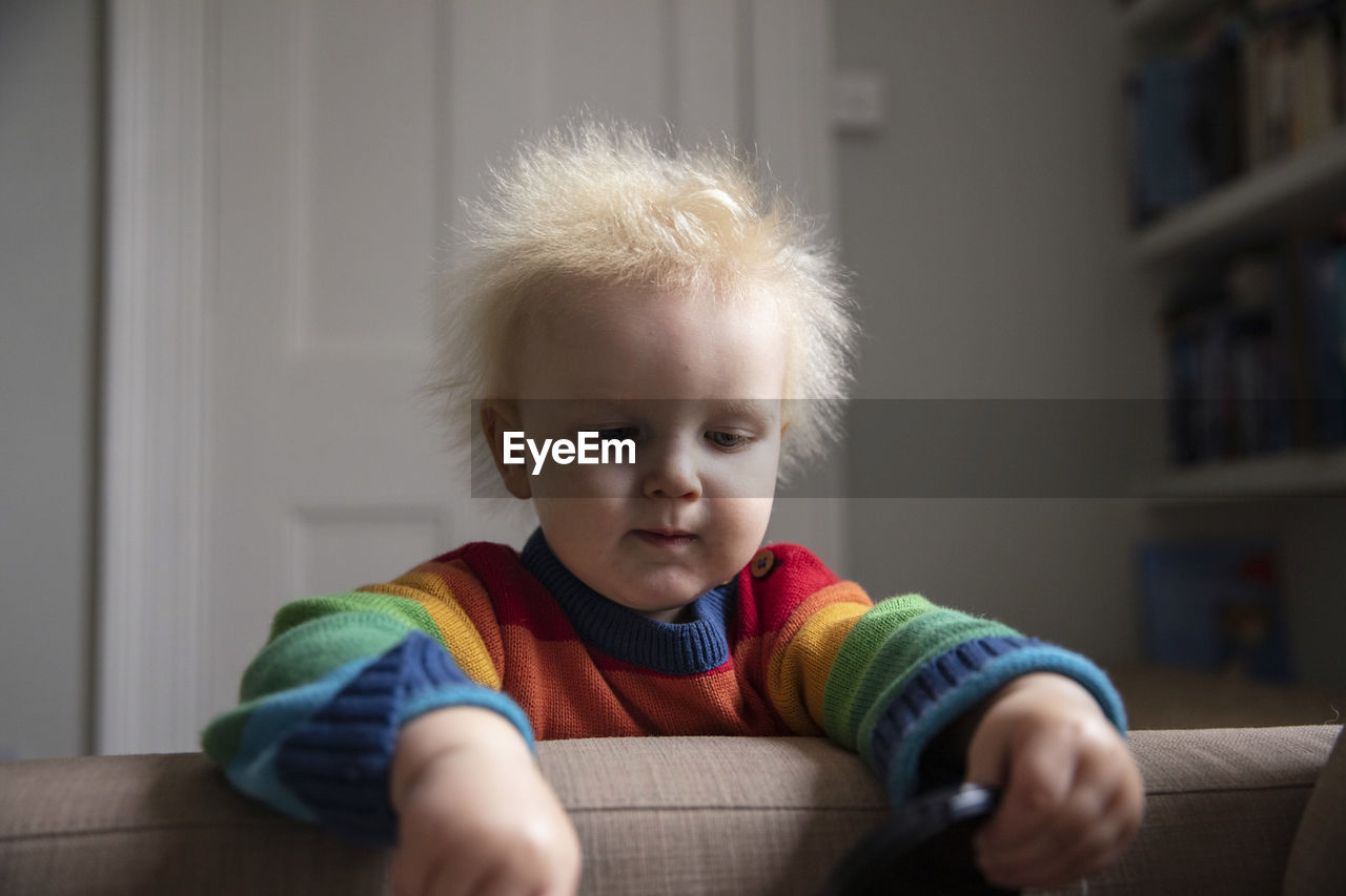 Close-up of cute baby boy sitting on sofa