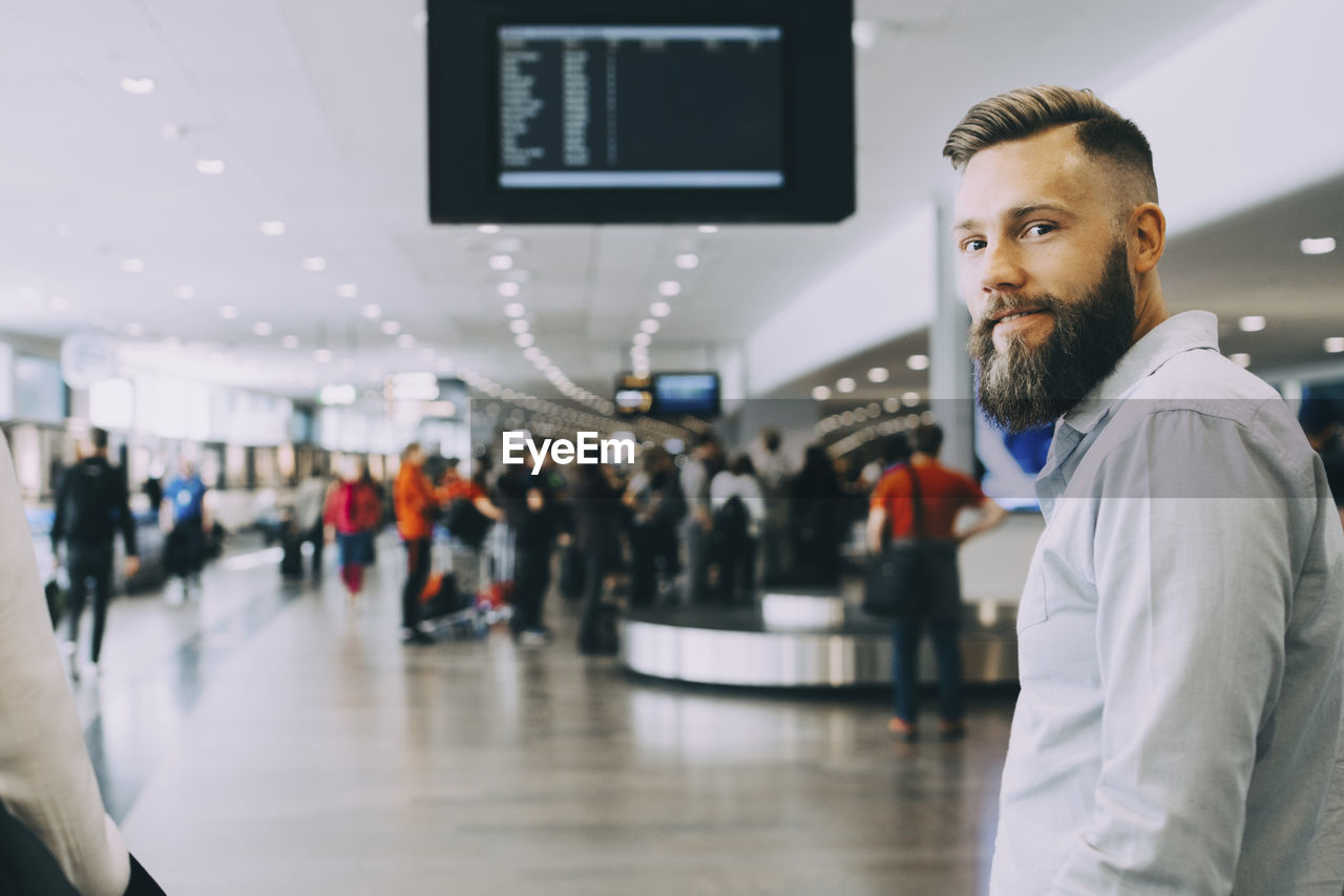 Portrait of smiling businessman standing with businesswoman at airport