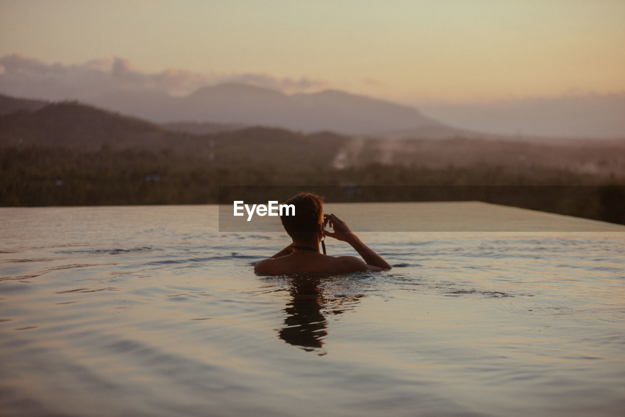 Full length of woman in lake against sky during sunset