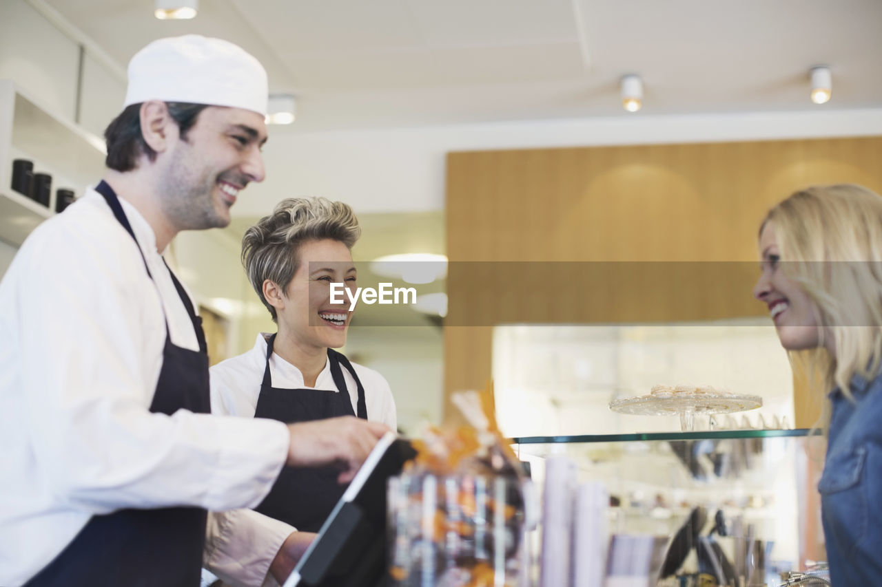 Happy worker attending female customer at cafe counter