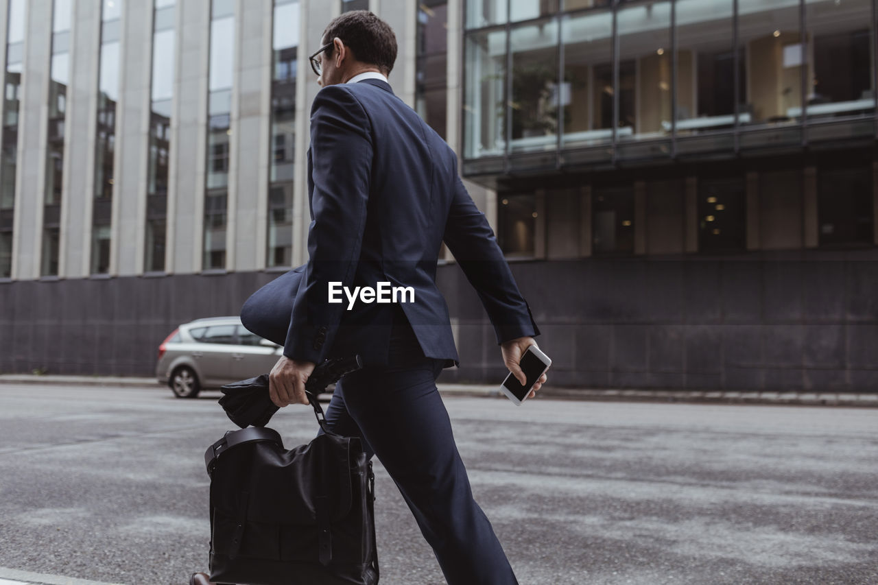 Side view of businessman with bag walking in city