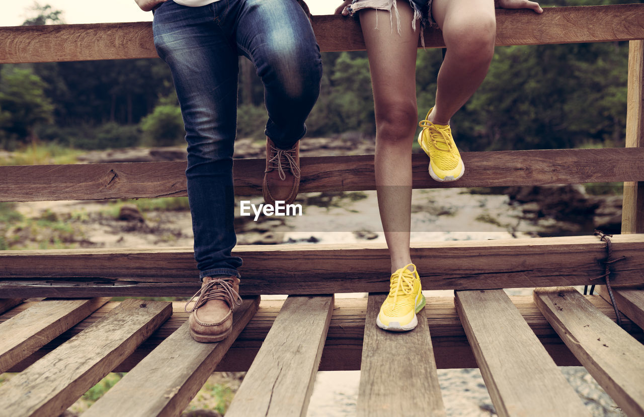 Low section of man and woman standing on wooden plank