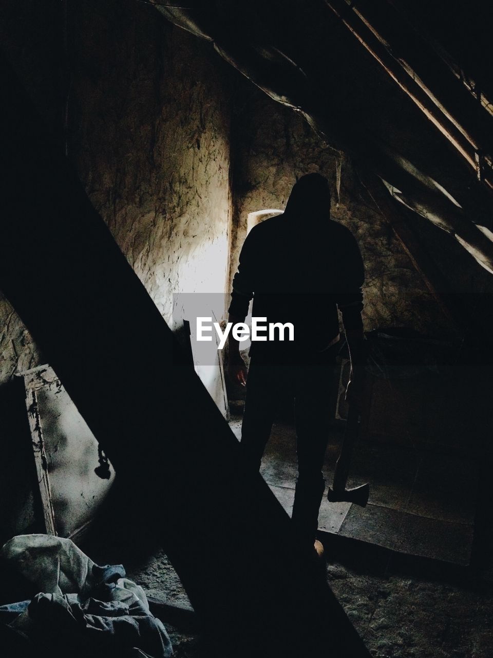 Rear view of man with axe standing in abandoned house