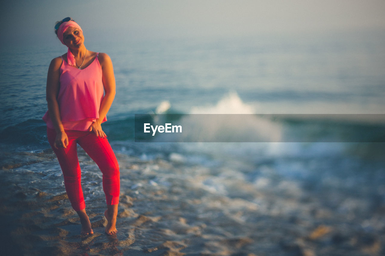 Full length of young woman standing at beach