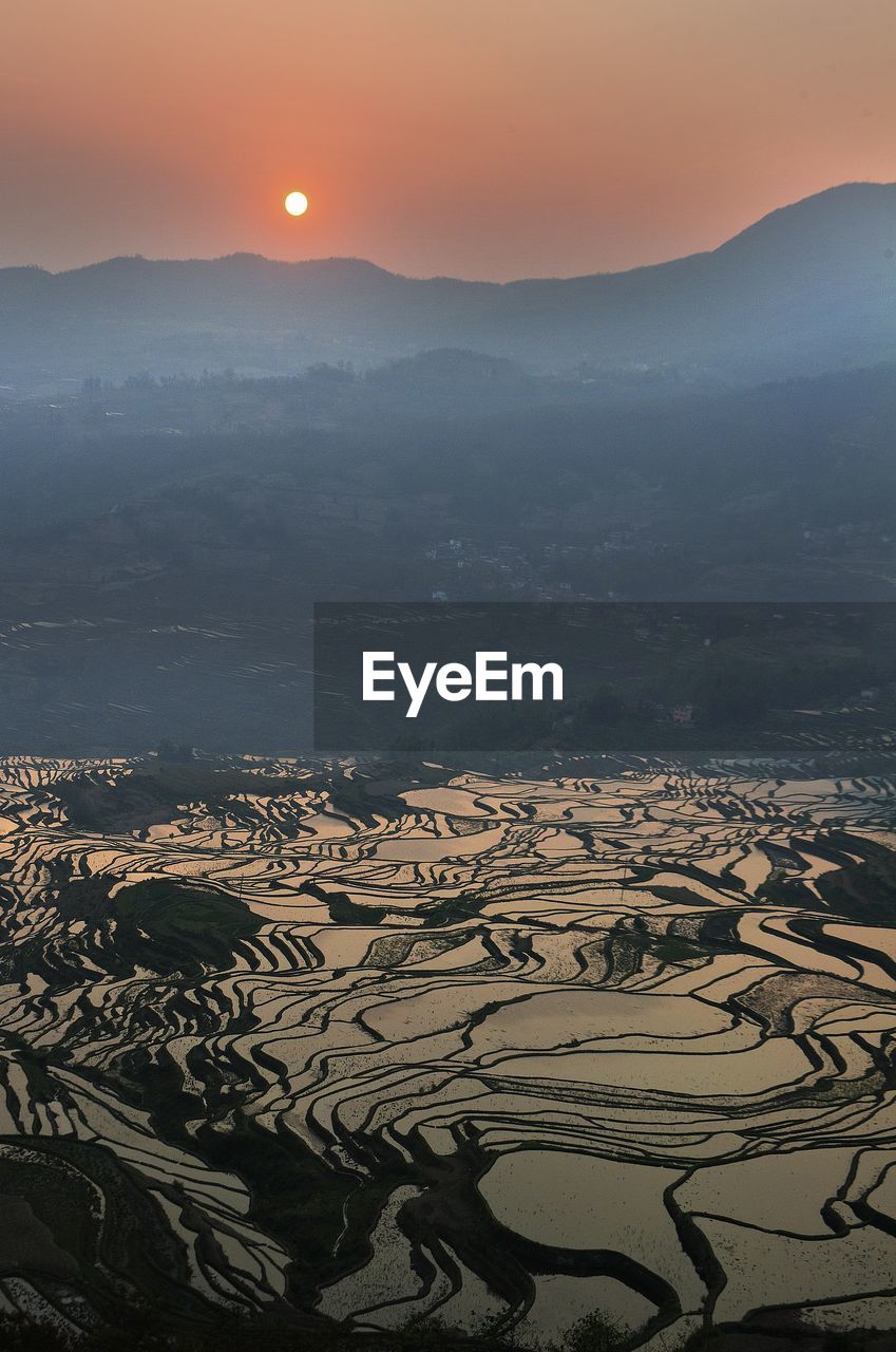 Aerial view of landscape in foggy weather during sunset