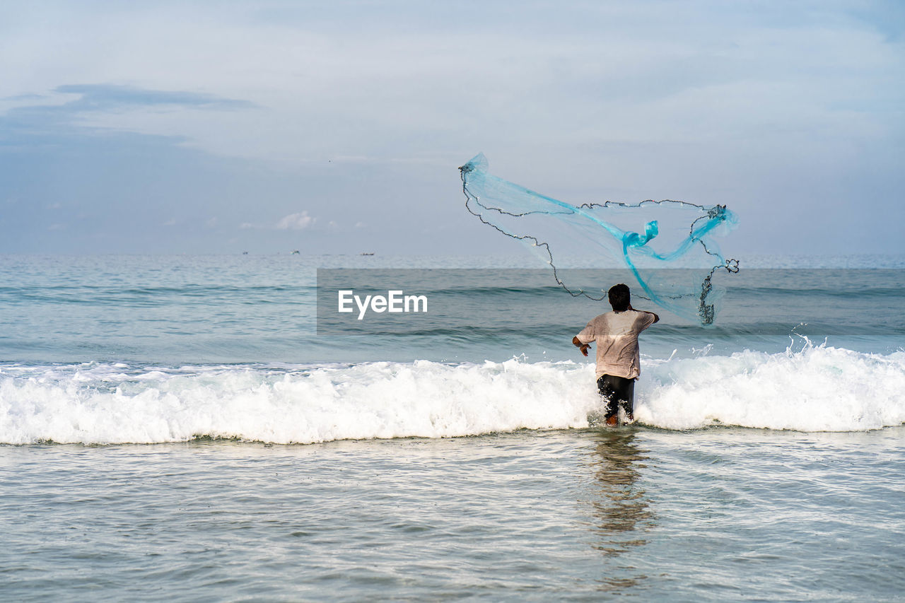 Full length rear view of person at sea shore against sky